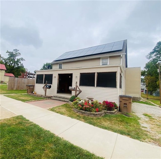 view of front of house featuring a front yard and solar panels