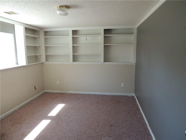 carpeted spare room with a textured ceiling, visible vents, and baseboards