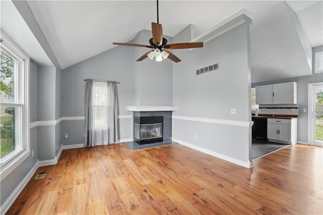2016 NE Summerfield Ct, Blue Springs, MO 64029 - unfurnished living room featuring ceiling fan, light wood-type flooring, a tiled fireplace, and high vaulted ceiling