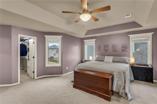 bedroom with baseboards, a raised ceiling, visible vents, and light colored carpet