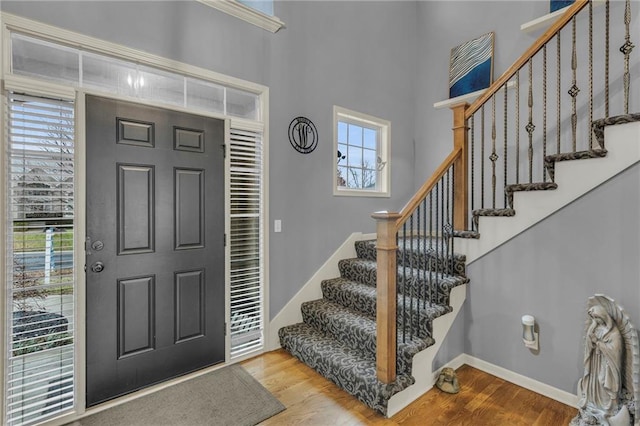 entryway with stairs, baseboards, and wood finished floors