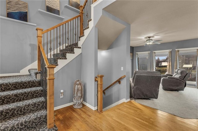 stairs featuring ceiling fan, wood finished floors, and baseboards