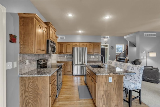 kitchen with visible vents, a breakfast bar area, appliances with stainless steel finishes, and a sink