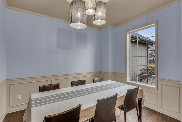 dining area featuring crown molding, wainscoting, dark wood finished floors, and a decorative wall