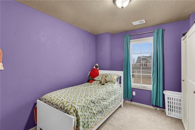 carpeted bedroom featuring visible vents, a textured ceiling, and baseboards