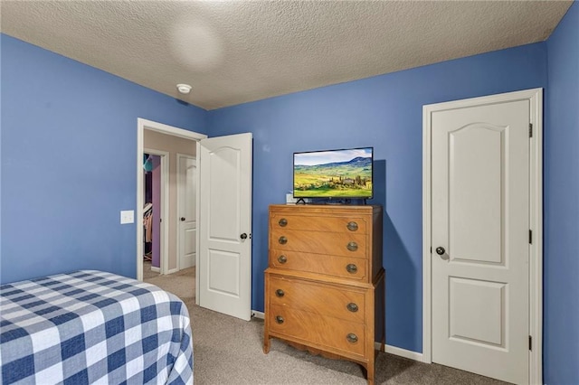 bedroom featuring light colored carpet, a textured ceiling, and baseboards