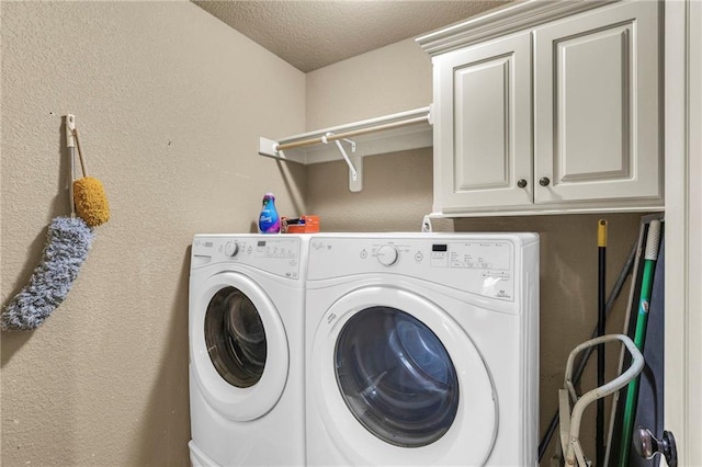 laundry area with cabinet space, a textured ceiling, washer and dryer, and a textured wall