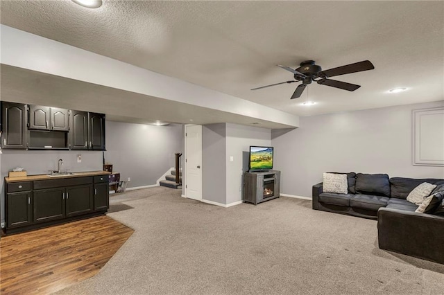 living room with a ceiling fan, light colored carpet, baseboards, and stairs