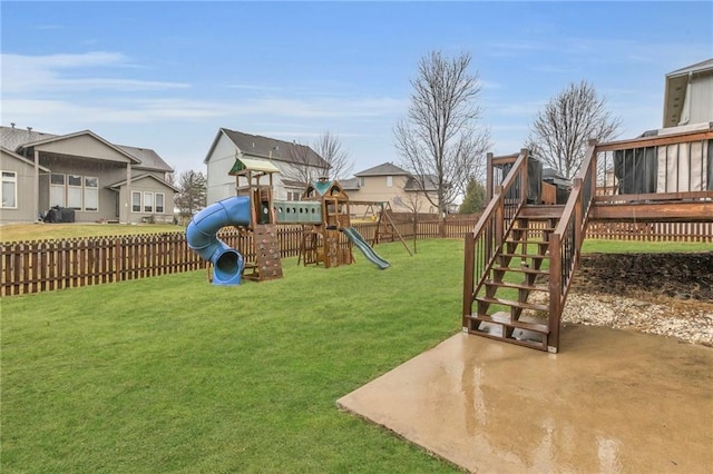 view of playground featuring fence, stairs, a lawn, a wooden deck, and a patio area