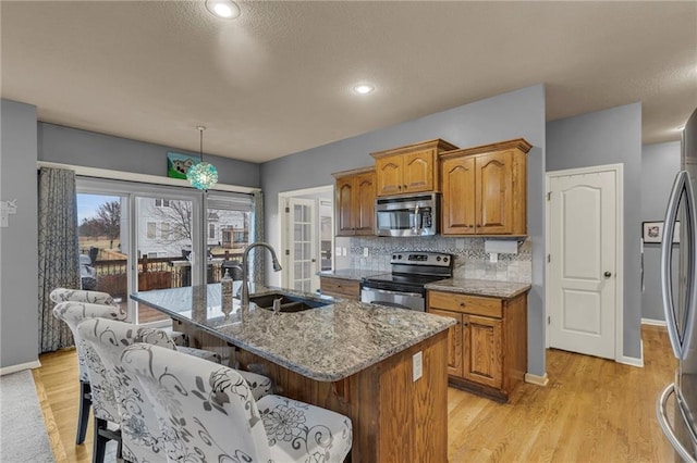 kitchen with stainless steel appliances, tasteful backsplash, brown cabinetry, and a sink