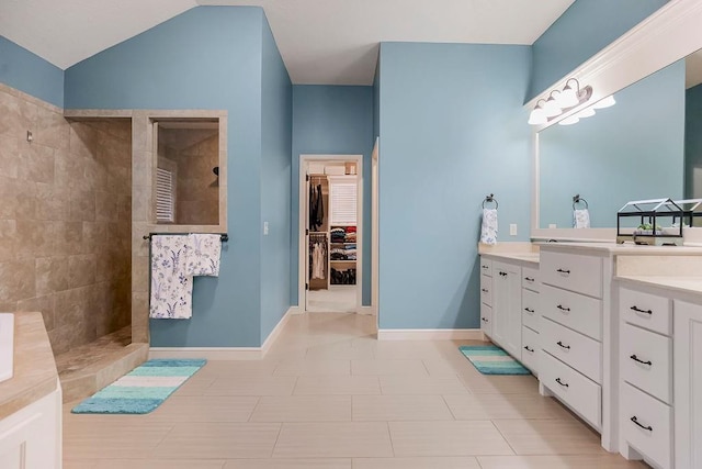 bathroom featuring vanity, vaulted ceiling, and a tile shower