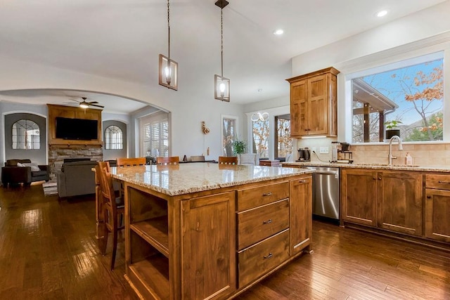 kitchen with sink, a stone fireplace, dishwasher, a center island, and decorative light fixtures