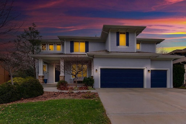 prairie-style home featuring a garage, driveway, a porch, and stucco siding