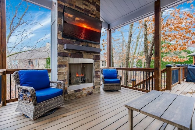 wooden deck featuring an outdoor stone fireplace