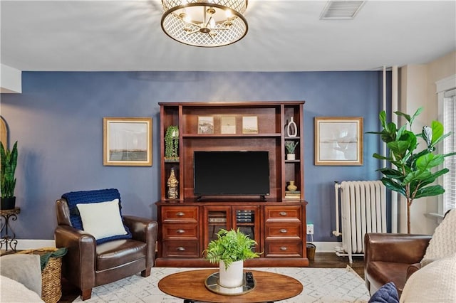 living area featuring baseboards, visible vents, and radiator heating unit