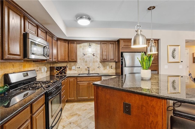 kitchen with a kitchen island, a sink, appliances with stainless steel finishes, brown cabinetry, and dark stone countertops