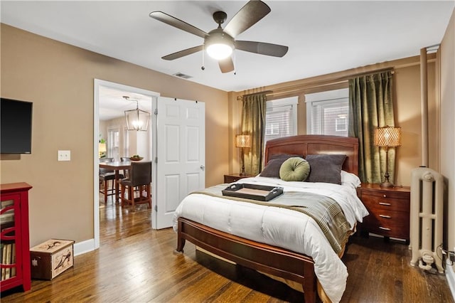 bedroom with multiple windows, dark wood-style flooring, visible vents, and radiator