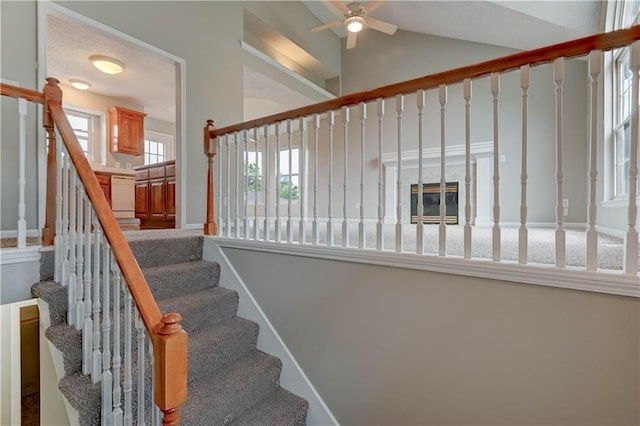 828 SW Harvest Dr, Grain Valley, MO 64029 - staircase with healthy amount of natural light, a ceiling fan, a glass covered fireplace, and high vaulted ceiling