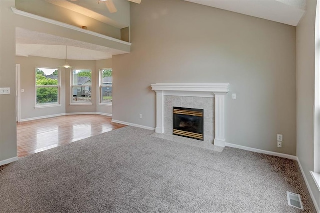 828 SW Harvest Dr, Grain Valley, MO 64029 - unfurnished living room featuring carpet, ceiling fan, vaulted ceiling, baseboards, and a tile fireplace