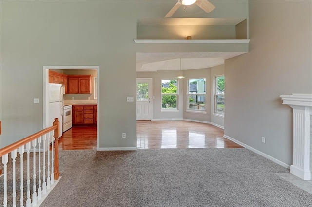 828 SW Harvest Dr, Grain Valley, MO 64029 - unfurnished living room with ceiling fan, light carpet, baseboards, and a towering ceiling