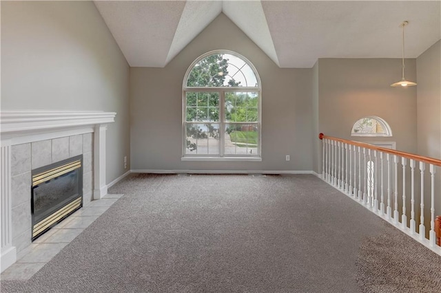 828 SW Harvest Dr, Grain Valley, MO 64029 - unfurnished living room featuring carpet floors, vaulted ceiling, a tile fireplace, and baseboards