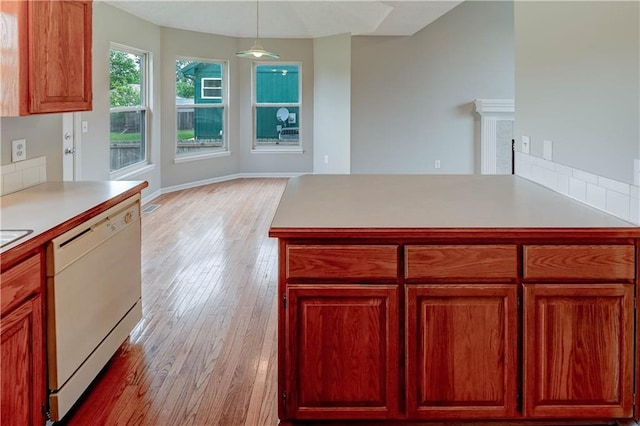 828 SW Harvest Dr, Grain Valley, MO 64029 - kitchen featuring dishwasher, light wood-style flooring, light countertops, decorative light fixtures, and a peninsula