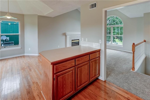828 SW Harvest Dr, Grain Valley, MO 64029 - kitchen with light wood-style floors, baseboards, light countertops, a fireplace, and decorative light fixtures