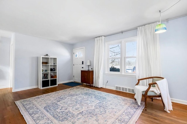 living area with visible vents, baseboards, and wood finished floors