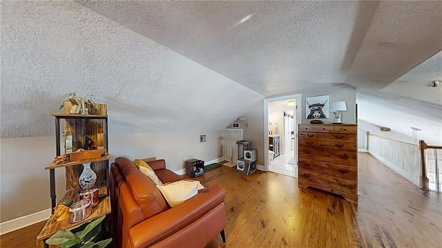 living area with hardwood / wood-style flooring, lofted ceiling, and a textured ceiling