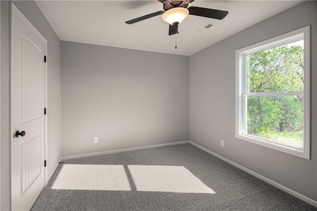 carpeted empty room featuring a ceiling fan, visible vents, plenty of natural light, and baseboards