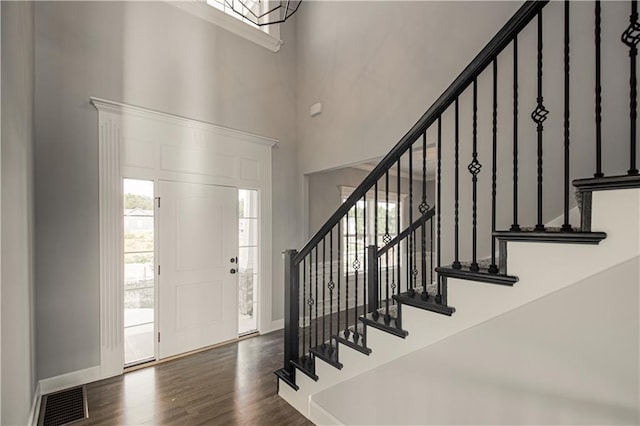 entryway with visible vents, stairway, a high ceiling, wood finished floors, and baseboards