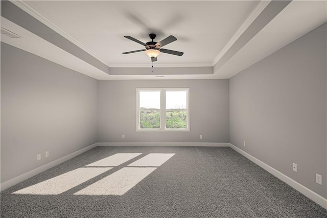 carpeted empty room with ornamental molding, a tray ceiling, baseboards, and a ceiling fan