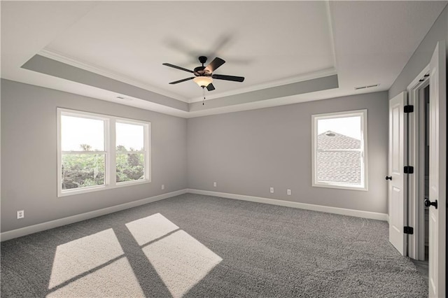 carpeted empty room featuring a raised ceiling and baseboards