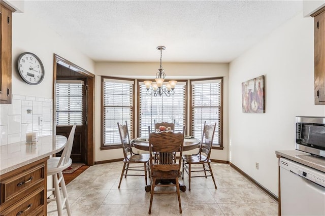 tiled dining room featuring an inviting chandelier and a textured ceiling