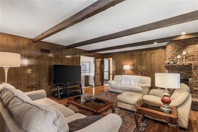 living room with beamed ceiling, hardwood / wood-style floors, a fireplace, and wooden walls