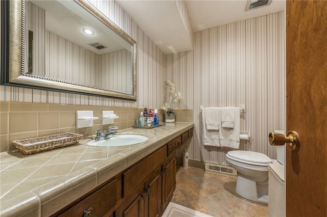 bathroom with tasteful backsplash, vanity, and toilet