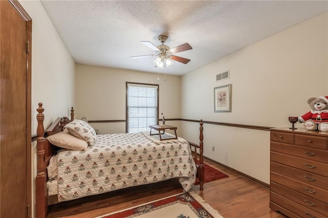 bedroom featuring hardwood / wood-style flooring, ceiling fan, and a textured ceiling