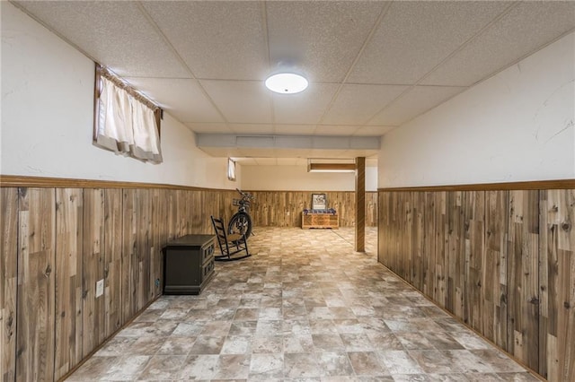 basement with a paneled ceiling and wooden walls