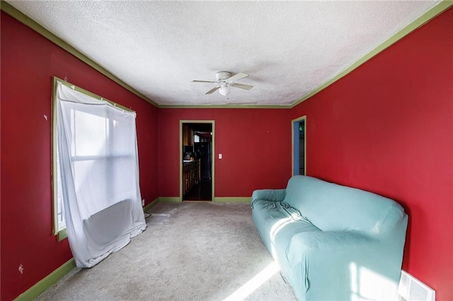 sitting room with ceiling fan, carpet flooring, and a textured ceiling