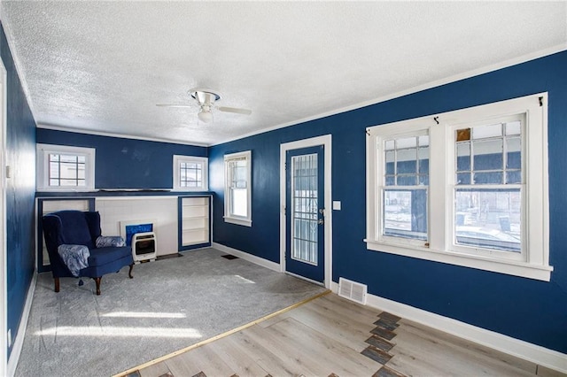 foyer with crown molding, ceiling fan, hardwood / wood-style floors, heating unit, and a textured ceiling