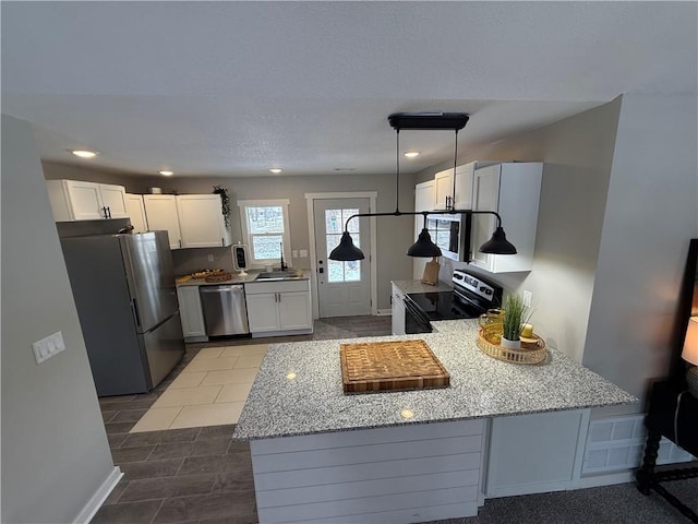 kitchen with light stone counters, kitchen peninsula, white cabinets, and appliances with stainless steel finishes