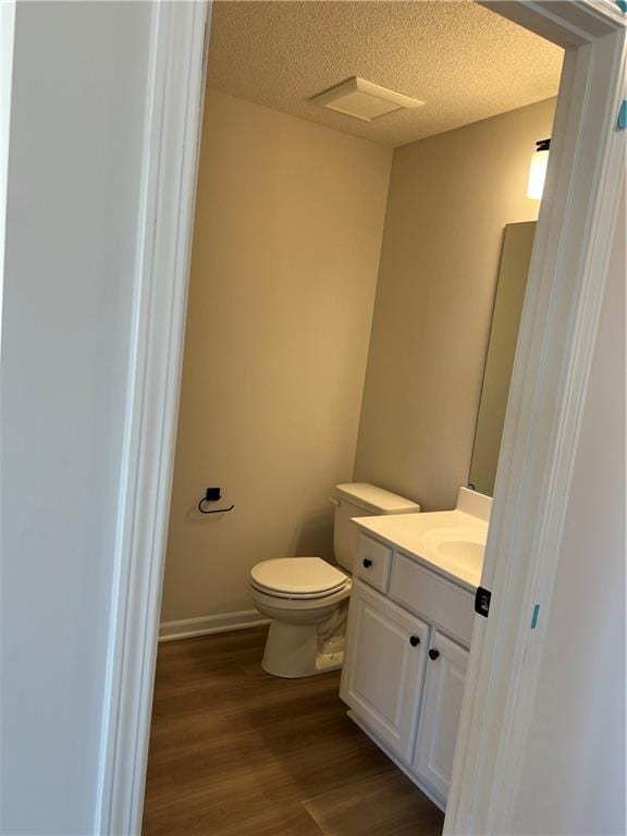 bathroom with toilet, vanity, a textured ceiling, and wood finished floors