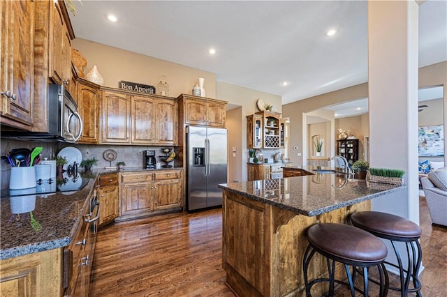 kitchen featuring dark stone countertops, decorative backsplash, dark hardwood / wood-style floors, and appliances with stainless steel finishes