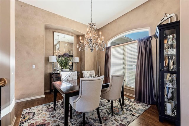 dining area with a notable chandelier and dark hardwood / wood-style flooring