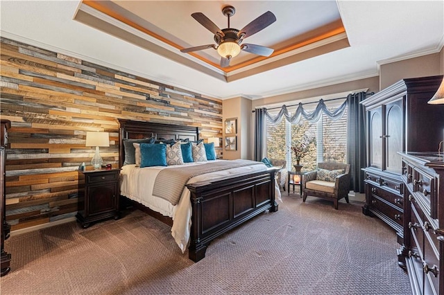 bedroom with ceiling fan, dark colored carpet, a tray ceiling, ornamental molding, and wood walls