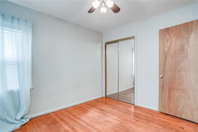 unfurnished bedroom with ceiling fan, a closet, and light wood-type flooring