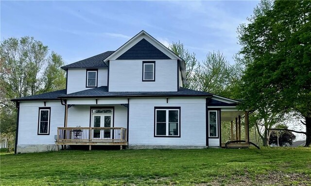 rear view of house with a lawn, a deck, and a shingled roof