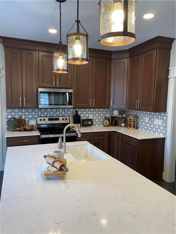 kitchen featuring decorative backsplash, decorative light fixtures, a sink, stainless steel appliances, and recessed lighting