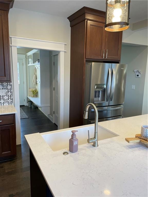 kitchen with backsplash, light countertops, a sink, dark wood-style floors, and stainless steel fridge