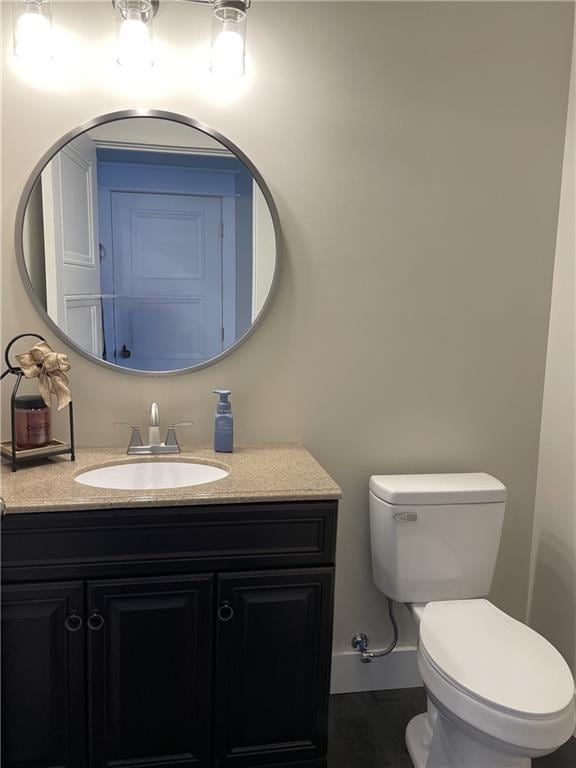 bathroom with toilet, baseboards, and vanity